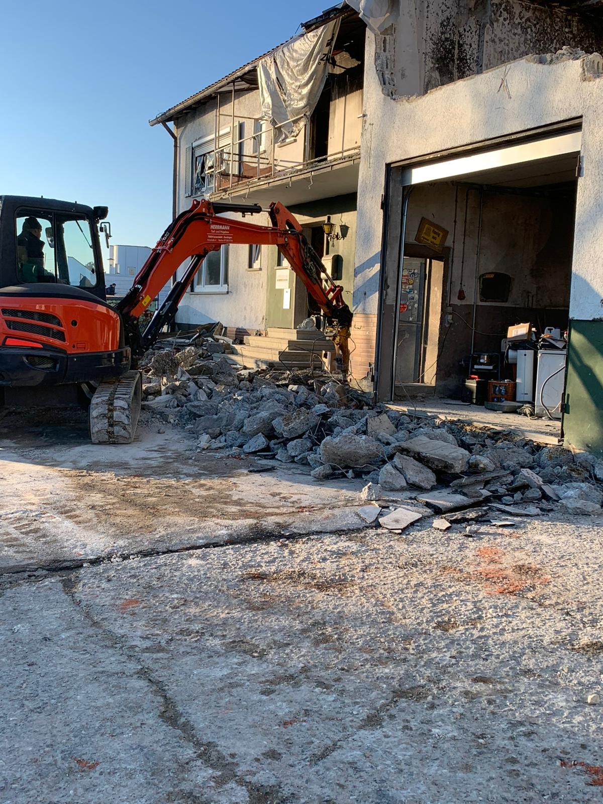 Minibagger Kubota mit Hydraulikhammer bei Abbrucharbeiten an einem Gebäude