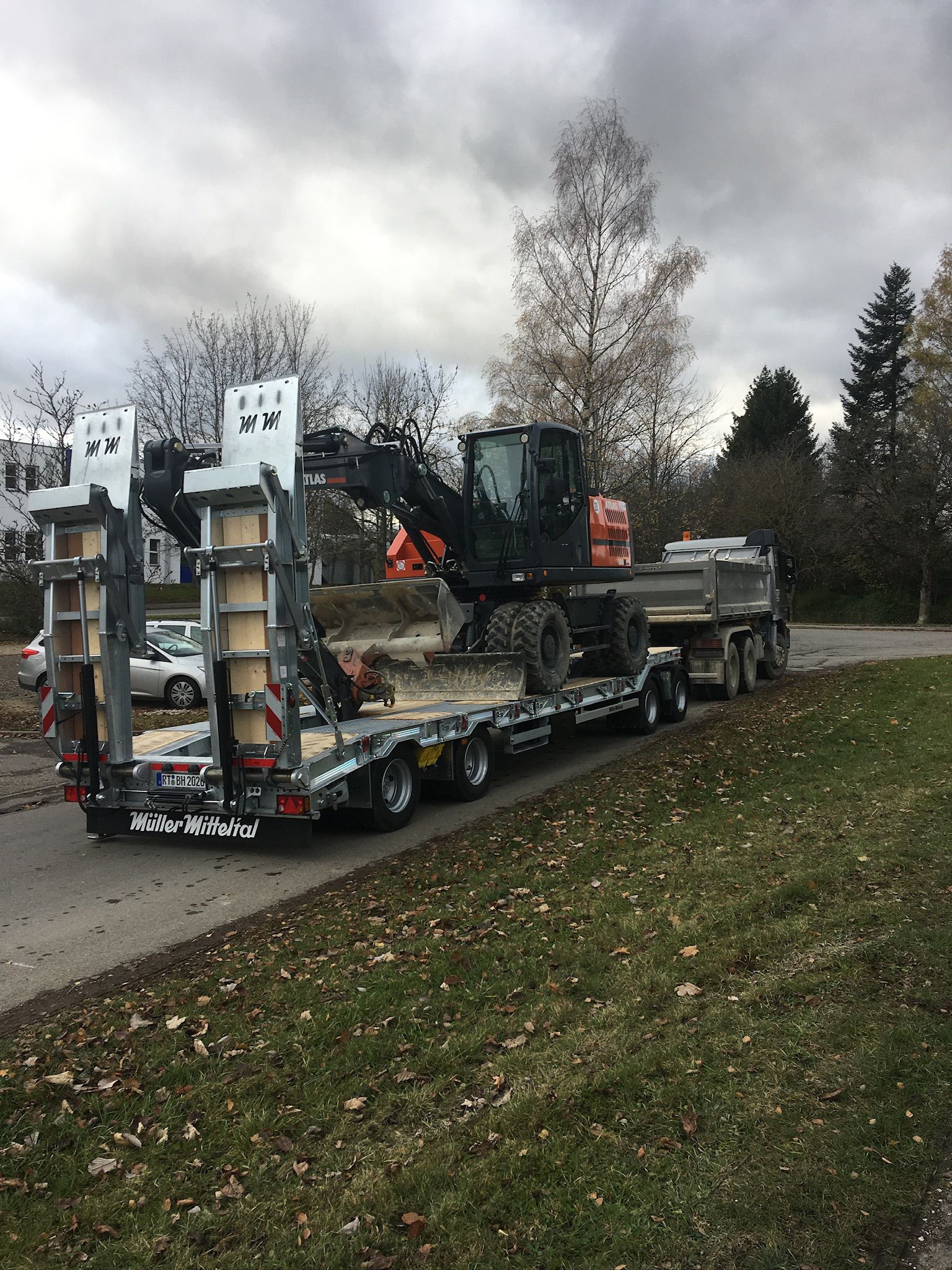 Mobilbagger Atlas mit Räumschild, verladen auf dem Tieflader
