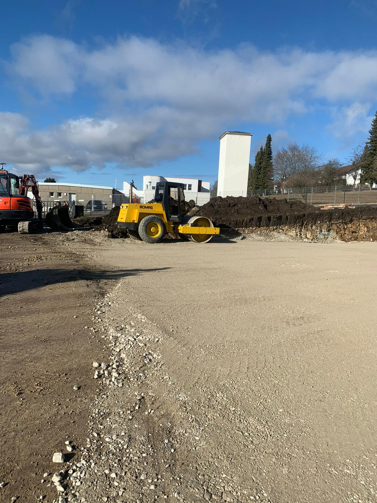 Bomag Walze auf einem verdichteten Planum, dahinter ein Bagger