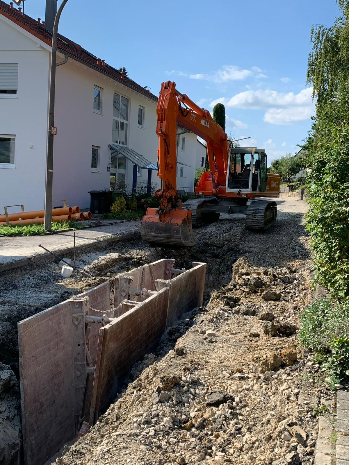Kettenbagger Atlas 1704 LC an einem mit Kanaldielen gesicherten Rohrgraben in einer Wohnstraße